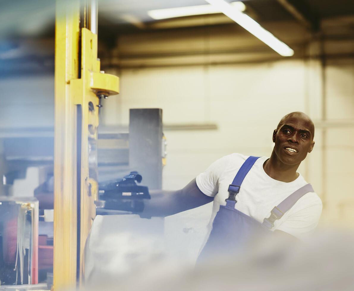 male looking away while operating a machine in a warehouse.
male looking away while operating a machine in a warehouse.